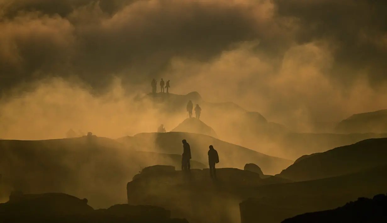 Para penganut Hindu dari komunitas Tengger terlihat melalui awan rendah saat matahari terbit ketika mereka mendaki gunung berapi aktif Bromo untuk mempersembahkan sesaji berupa beras, buah-buahan, ternak, dan barang-barang lainnya sebagai bagian dari festival Yadnya Kasada di Probolinggo, Jawa Timur, Senin 1 Juni 2026. (JUNI KRISWANTO/AFP)