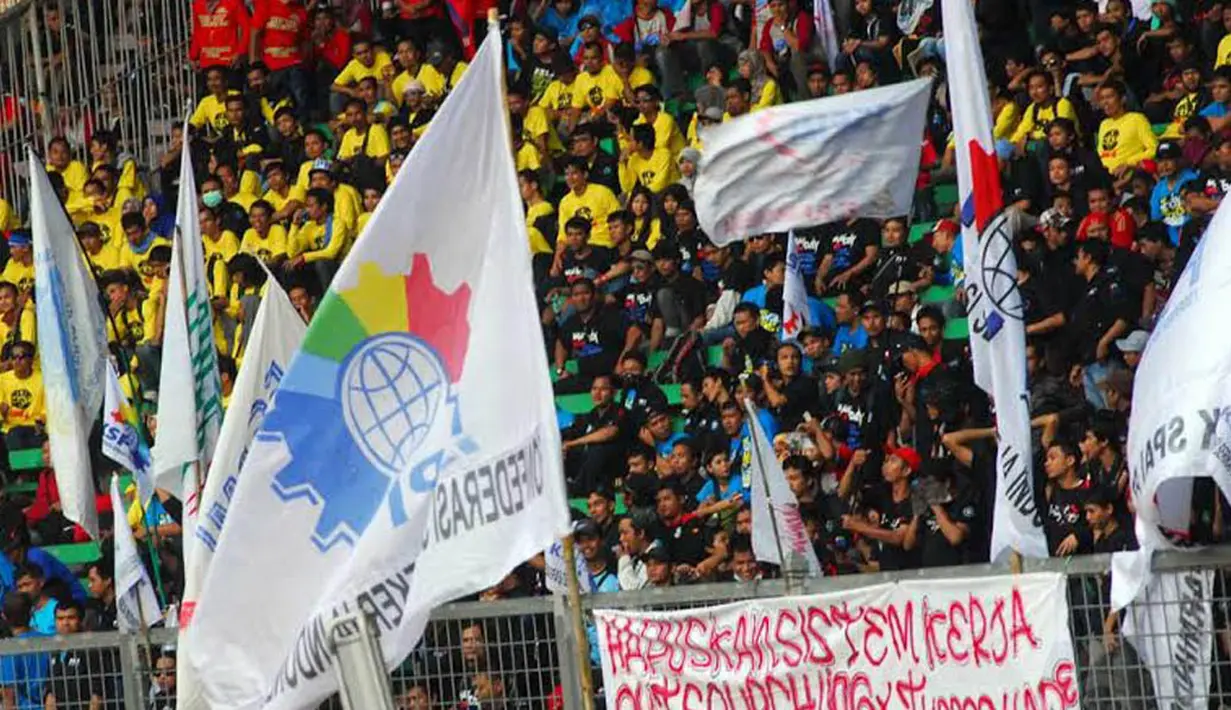 Sebuah spanduk yang berisi salah satu permintaan untuk menghapus sistem kerja outsourching terpasang di pagar sisi dalam GBK (Liputan6.com/Miftahul Hayat)