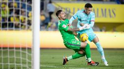 Pemain Barcelona, Vitor Roque, berebut bola dengan kiper Las Palmas pada laga La Liga 2023/2024 jornada 19 di Estadio de Gran Canaria, Jumat (5/1/2024). Barca menang dengan skor tipis 2-1. (AFP/Desiree Martin)