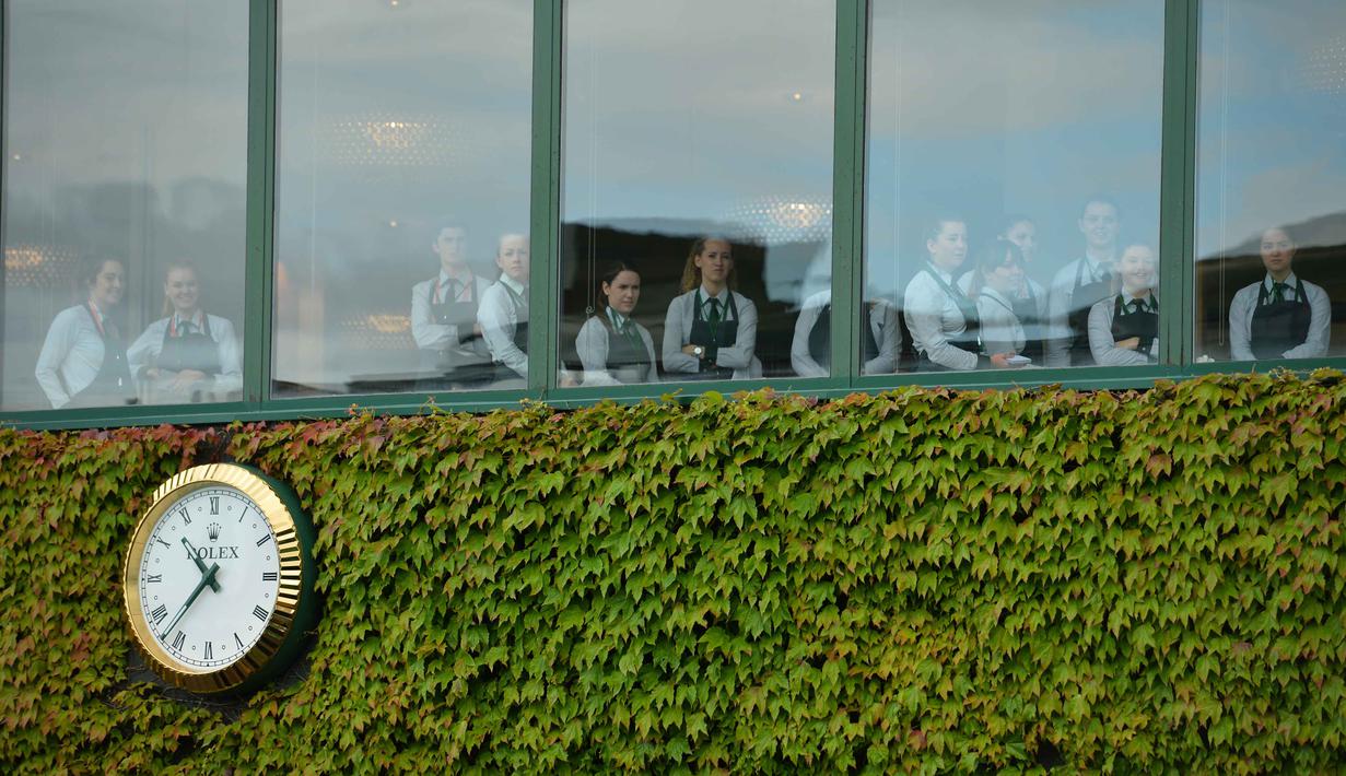 Staff restoran menyaksikan aksi pemain Serbia, Novak Djokovic saat berlatih sebelum melawan pemain Inggris Raya,  James Ward  pada Tenis Wimbledon Championships 2016 di The All England Lawn Tennis Club, Wimbledon,  London, (27/6/2016). (AFP/ Glyn Kirk)