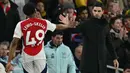 Pemain Arsenal, Myles Lewis-Skelly melakukan tos dengan pelatih Mikel Arteta saat digantikan dalam laga lanjutan Liga Inggris 2024/2025 melawan Manchester City di Emirates Stadium, London, Minggu (03/02/2025). (AFP/Glyn Kirk)