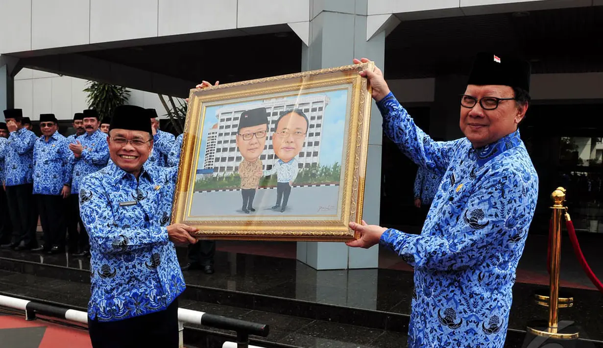 Dirjen Otonomi Daerah Kemdagri, Djohermansyah Djohan (kiri) menerima karikatur dari Mendagri Tjahjo Kumolo, Jakarta, Senin (22/12/2014). (Liputan6.com/Johan Tallo)