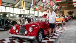 Foto yang diambil pada 14 Oktober 2025 ini menunjukkan Jos Dharmawan, pengusaha dan pendiri Museum Mobil Antik Kebon, berpose di samping Morgan Plus 8 tahun 1990 di antara koleksi mobil klasiknya di museumnya di Bali. Inilah garasi impian Jos Dharmawan, seorang kolektor yang telah menyulap ruang privatnya menjadi sebuah museum hidup, untuk ratusan mobil klasik dan antik. (Dicky Bisinglasi/AFP)