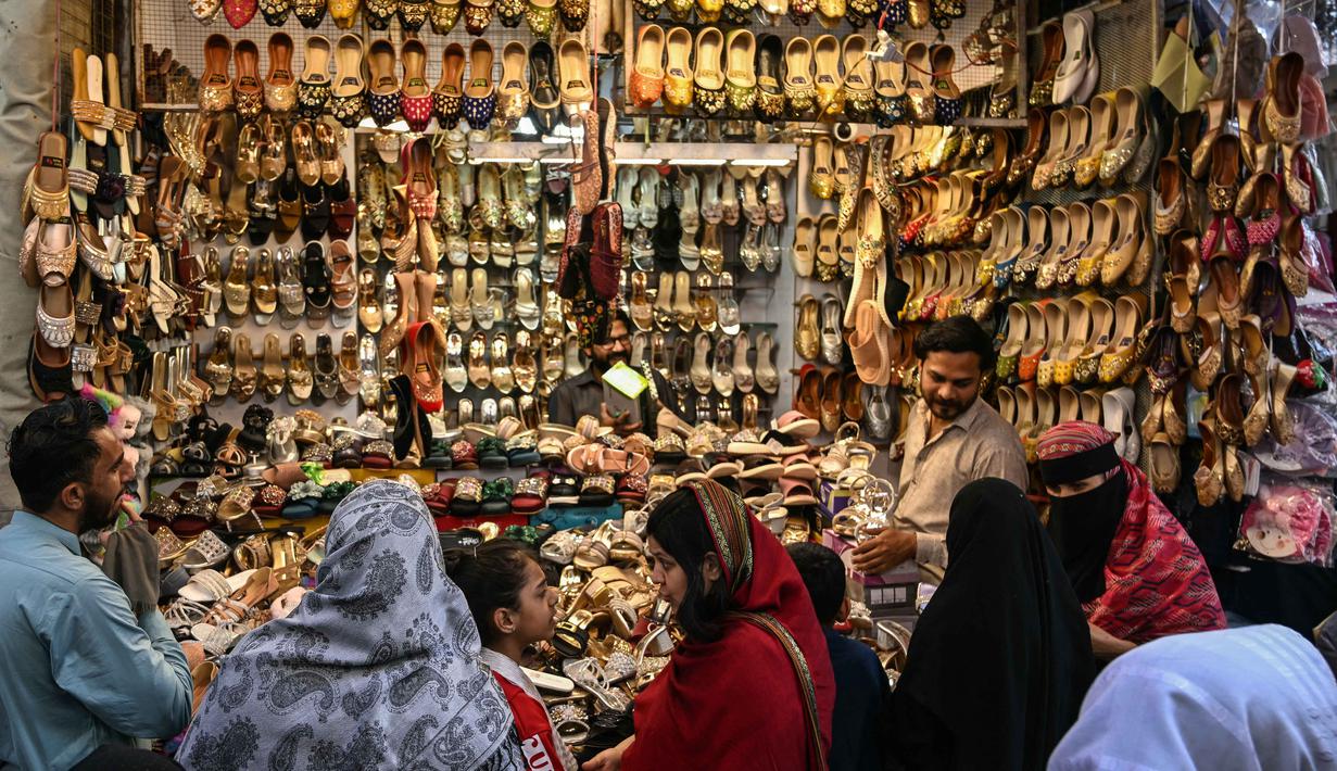 Suasana terlihat sibuk dan meriah dipadati warga yang akan membeli pakaian, sepatu, dan kebutuhan dekorasi Hari Raya Idul Fitri. Tampak dalam foto, Umat Muslim Pakistan berbelanja untuk perayaan Idul Fitri, selama minggu terakhir bulan suci Ramadan 1447 Hijriah, di Rawalpindi pada 14 Maret 2026. (Farooq NAEEM/AFP)