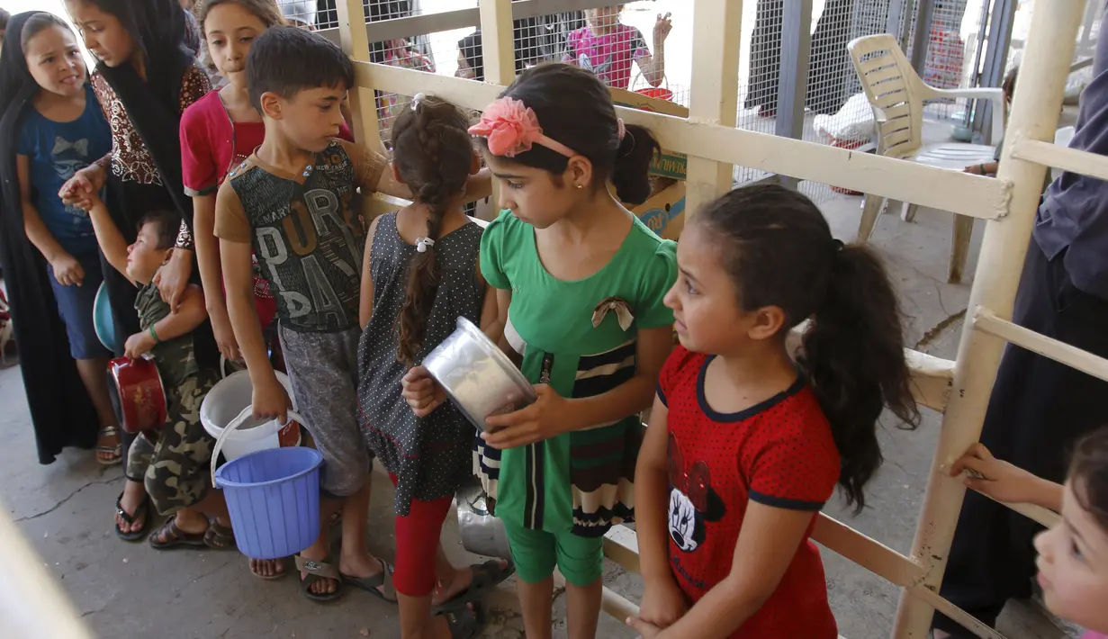 Sejumlah anak kecil menunggu makanan buka puasa gratis yang didistribusikan bagi yang membutuhkan selama bulan puasa di masjid Abdul Qadir al-Gailani, Baghdad, Rabu (24/6/2015). (REUTERS/Khalid al-Mousily)
