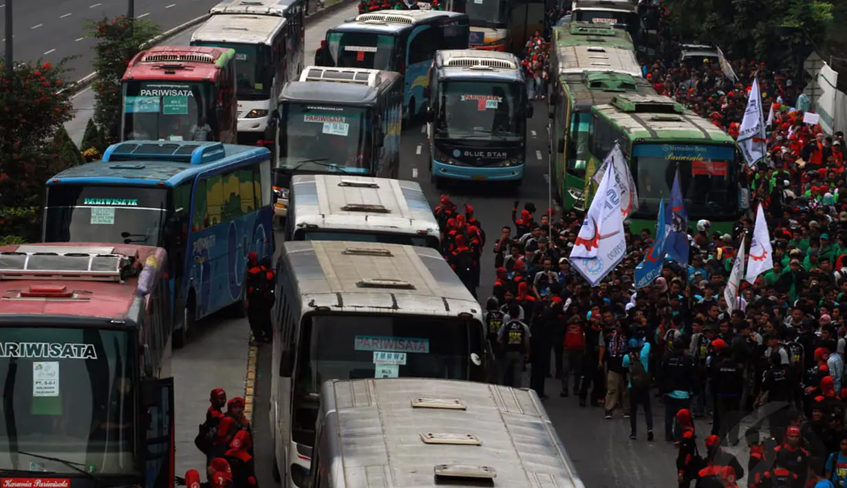 Massa yang terjebak macet memilih turun dari bus sambil mengibarkan bendera organisasi, Kamis (1/5/14). (Liputan6.com/Johan Tallo)