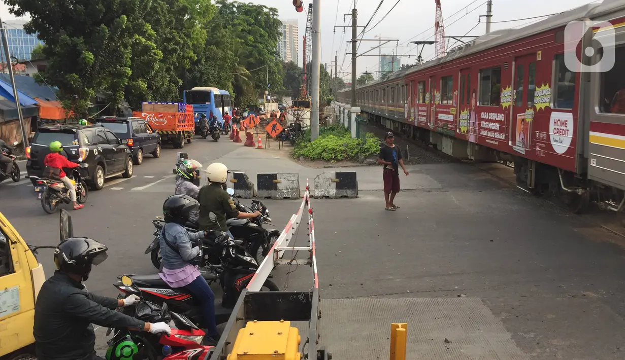 Kendaraan menunggu kereta melintas di jalur putar balik yang juga perlintasan sebidang di kawasan Tanjung Barat, Jakarta, Kamis (19/12/2019). Mulai Sabtu (21/12) mendatang, jalur putar balik itu akan ditutup, terkait proyek pembangunan flyover di kawasan tersebut. (Liputan6.com/Immanuel Antonius)