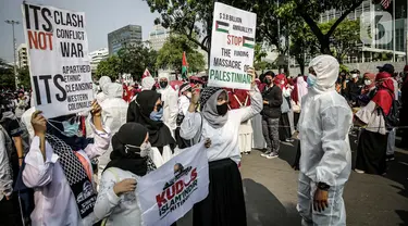 Petugas Satgas COVID-19 dari personel kepolisian meminta peserta aksi solidaritas untuk Palestina menjaga protokol kesehatan di depan Kedutaan Besar AS, Jakarta, Selasa (18/5/2021). Massa mengutuk dan mengecam keras kekerasan yang dilakukan Israel atas Palestina. (Liputan6.com/Faizal Fanani)