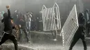 Demonstran merusak pagar saat terjadi bentrok dengan polisi di sekitar Kongres di Valparaiso, Chili. Sabtu (21/5). Peristiwa itu menyebabkan sejumlah gedung terbakar dan seorang polisi tewas. (AFP Photo/Claudio Reyes)
