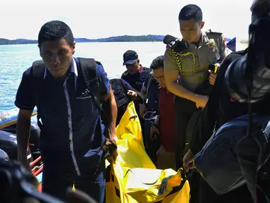 Anggota kepolisian bersiap turun dari kapal sambil mengangkat kantong jenazah berisi puing-puing dan barang-barang dari jatuhnya pesawat jenis M-28 Skytrcuk milik Polri di Pelabuhan Telaga Punggur, Batam, Kepri, Minggu (4/12). (Rezza HERDIYANTO/AFP)