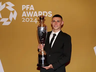 Gelandang Manchester City, Phil Foden berpose dengan trofi penghargaan Pemain Terbaik Pria versi Asosiasi Pemain Sepak Bola Profesional (PFA) di Opera House Manchester, Inggris, Selasa (20/8/2024). (Peter Byrne/PA via AP)