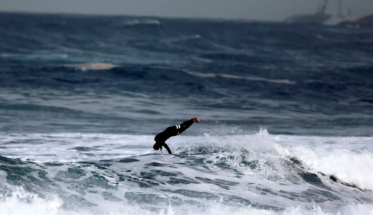 Seorang peserta melompat setelah berhasil menaklukan ombak selama mengikuti dalam kompetisi surfing di laut Mediterania di Ashdod, Israel, (17/11). (REUTERS/Amir Cohen)