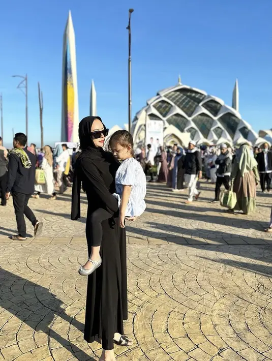 Aura Kasih mengenakan long dress hitam dipadukan pashmina saat Idul Adha. @aurakasih.