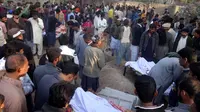 Sejumlah orang berkumpul di pemakaman korban tewas minuman keras oploson di Toba Tek Singh sekitar 338 km dari Islamabad, Selasa (27/12). Selain memakan korban jiwa, minuman oplosan rumahan itu juga membuat puluhan orang dilarikan ke rumah sakit (STR/AFP)