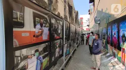 Warga melihat pameran foto jurnalistik karya pewarta foto Indonesia Tangerang di kawasan Pasar Lama, Tangerang, Minggu (30/5/2021). Pameran foto ini juga mengingatkan masyarakat terus menjaga protokol kesehatan untuk indonesia yang sehat. (Liputan6.com/Angga Yuniar)