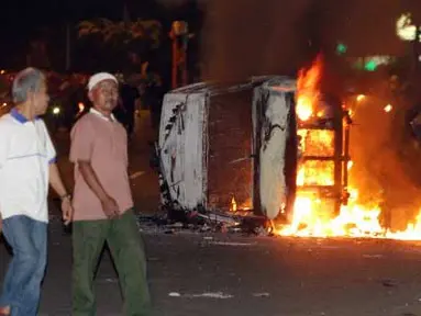 Sejumlah warga melihat mobil terbakar di jalan Diponegoro, Jakarta, Kamis malam (29/3). Aksi menolak kenaikan Bahan Bakar Minyak (BBM) berakhir bentrok. (Antara)