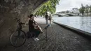 Seorang pria bermain cello di bawah jembatan di tepi Sungai Seine, Paris, Prancis, Minggu (11/7/2021). Prancis telah mengakhiri kewajiban mengenakan masker di luar ruangan dan pencabutan jam malam sejak pertengahan Juni lalu menyusul penurunan kasus COVID-19. (AP Photo/Lewis Joly)