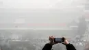 Warga mengabadikan gambar suasana kota Beijing yang diselimuti kabut asap tebal, Cina, 1 Januari 2017. (REUTERS/Stringer)
