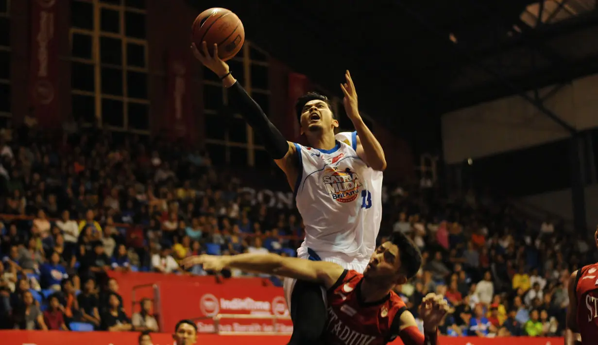 Pebasket Satria Muda Britama Jakarta, Gunawan (atas) melompat melewati hadangan pemain Stadium Jakarta di laga NBL Championship 2015, Sabtu (2/5/2015). Satria Muda unggul tipis 61-59 atas Stadium Jakarta. (Liputan6.com/Helmi Fithriansyah)