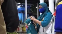 Seorang Pekerja Migran memasangkan masker pada anaknya begitu turun di Terminal Bangkalan