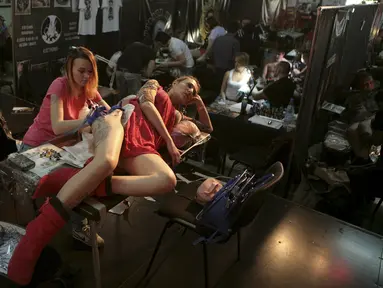 Seorang seniman membuat tato di punggung pelanggannya saat acara Festival Tato Internasional di Sochi, Rusia, (23/4). Sejumlah wanita tampak antusias untuk mentato tubuhnya di festival tato terbesar di negara tersebut. (REUTERS/Kazbek Basayev)
