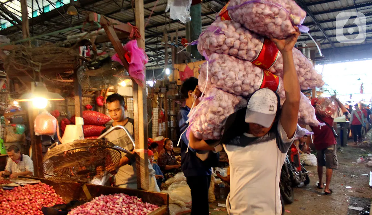 Pekerja membawa karung berisi bawang putih di Pasar Induk Kramatjati, Jakarta Timur, Rabu (5/2/2020). Kelangkaan pasokan bawang putih di dalam negeri berimbas tingginya harga komoditas tersebut yang mencapai kisaran Rp 57.500/kilogram. (merdeka.com/magang/ Muhammad Fayyadh)