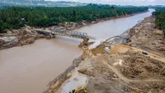 Foto udara menunjukkan sebuah ekskavator membersihkan puing-puing di dekat jembatan yang baru dibangun yang menghubungkan Aceh dan Provinsi Sumatera Utara di Sungai Peusangan, Distrik Bireuen, Provinsi Aceh, pada Selasa 9 Desember 2025. Pemerintah melalui Kementerian Pekerjaan Umum dan Perumahan Rakyat (PUPR) bersama TNI/Polri serta warga setempat terus cepat membangun jembatan bailey sebagai solusi darurat. (CHAIDEER MAHYUDDIN/AFP)