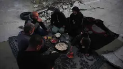 Mereka memasak dan makan di antara puing-puing bangunan, mencerminkan krisis kemanusiaan yang masih berlanjut. Tampak dalam foto, keluarga Suleiman berbuka puasa di bulan suci Ramadan di samping reruntuhan masjid, tempat mereka saat ini berlindung di Deir al-Balah, Jalur Gaza, Jumat 6 Maret 2026. (AP Photo/Abdel Kareem Hana)