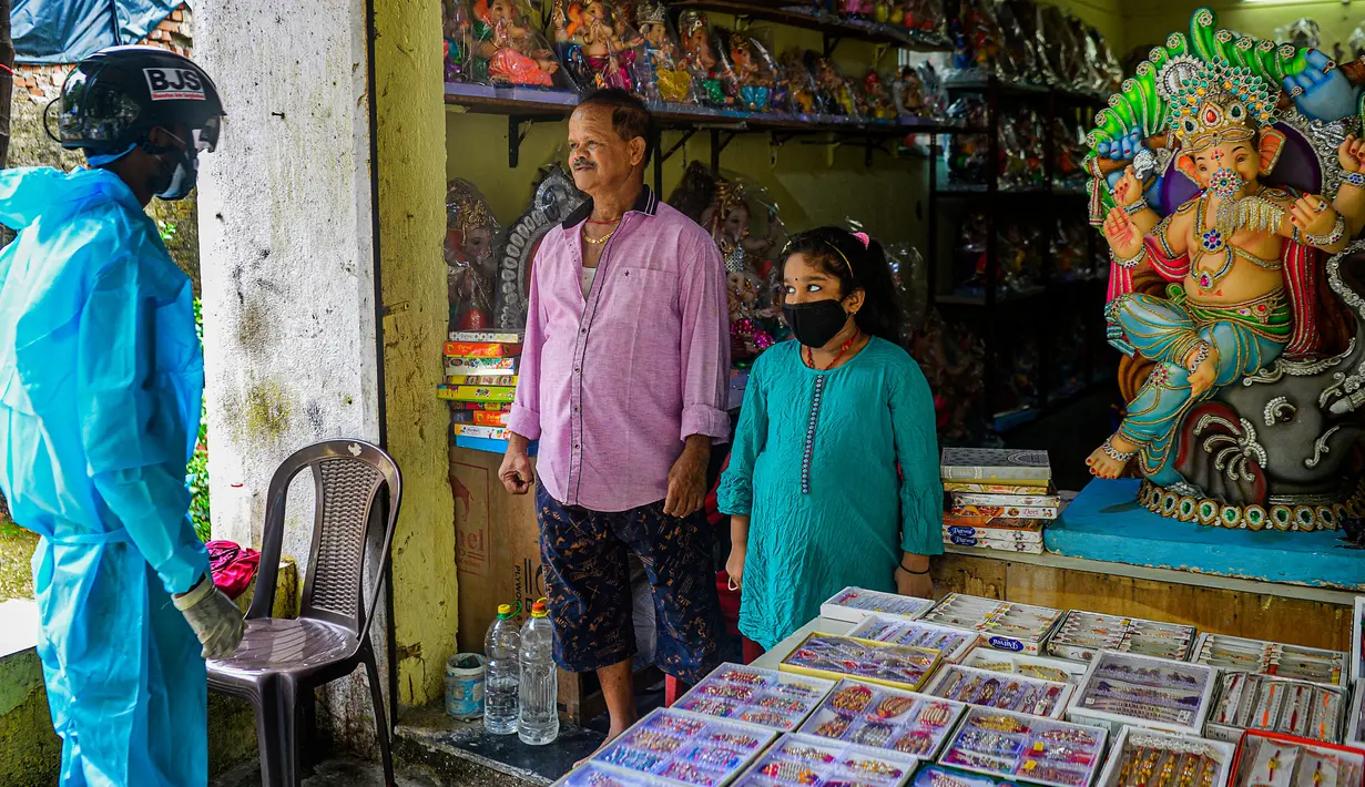Sukarelawan petugas kesehatan dari LSM India Bharatiya Jain Sanghatana mengenakan helm pintar saat proses screening kasus COVID-19 dari pintu ke pintu di Mumbai, 21 Juli 2020. Helm berteknologi tinggi ini mengidentifikasi kasus-kasus yang dicurigai di daerah kumuh dan padat. (INDRANIL MUKHERJEE/AFP)