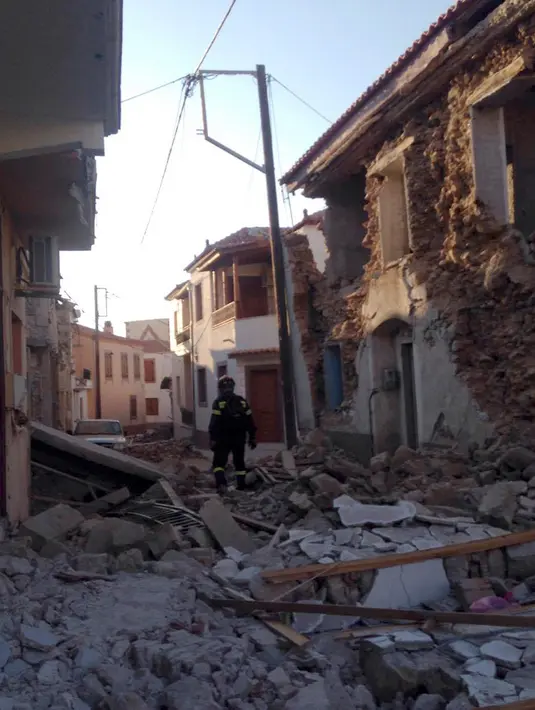 Petugas damkar berjalan di antara puing bangunan yang hancur setelah gempa bumi di pulau Lesbos, Yunani Timur, Senin (12/6). Gempa kuat tersebut, yang mengguncang pada siang hari, dirasakan di Ibu Kota Yunani, Athena. (AP Photo/Apostolis Paraskevopoulos)