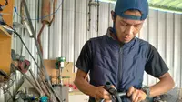Rixy Julian Rahmat, pemilik garasi DMR Custom tengah merakit kendaraan listrik. (Liputan6.com/Huyogo Simbolon)
