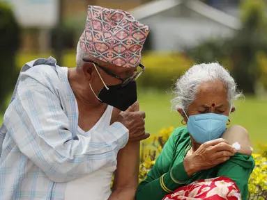 Pasangan lansia berpegangan tangan usai menerima vaksin virus corona COVID-19 AstraZeneca di Kathmandu, Nepal, Senin (9/8/2021). Hingga 8 Agustus 2021, kasus virus corona COVID-19 Nepal mencapai 717.486. (AP Photo/Niranjan Shrestha)