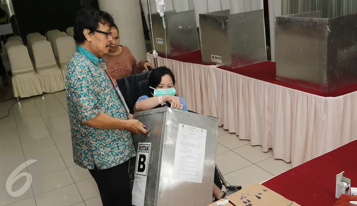 Pasein RSCM Meriati Irawan dibantu petugas memasukan surat suara saat mengikuti Pilkada DKI 2017 di TPS 15 RSCM, Jakarta, Rabu (15/2/2017). (Liputan6.com/Herman Zakharia)