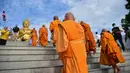 Biksu Buddha berjalan menuju patung Buddha raksasa saat mereka melakukan ritual keagamaan untuk menandai Hari Makha Bucha di kota Narathiwat, Thailand selatan (6/3/2023). Hari raya ini dirayakan pada saat bulan purnama di tiap bulan ketiga kalender Buddha. (AFP/Madaree Tohlala)