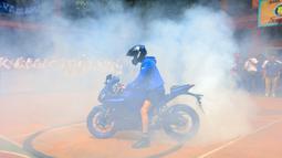 Pembalap asal Turki itu melakukan aksi freestyle dengan teknik wheelie dan donuts. Aksi donuts yang dilakukan Toprak Razgatlioglu sampai membuat SMK Negeri 39 Jakarta menjadi kepulan asap. (Bola.com/M Iqbal Ichsan)