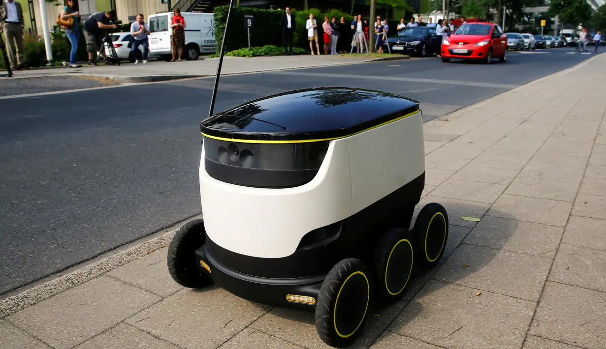 Mobil mungil beroda enam buatan Starship Technologies melintasi jalanan saat demonstrasi di kantor pusat Metro, Jerman, Selasa (7/6). Mobil bertenaga listrik tersebut disebut sebagai pengganti Pak Pos atau kurir di masa depan. (REUTERS/Wolfgang Rattay)