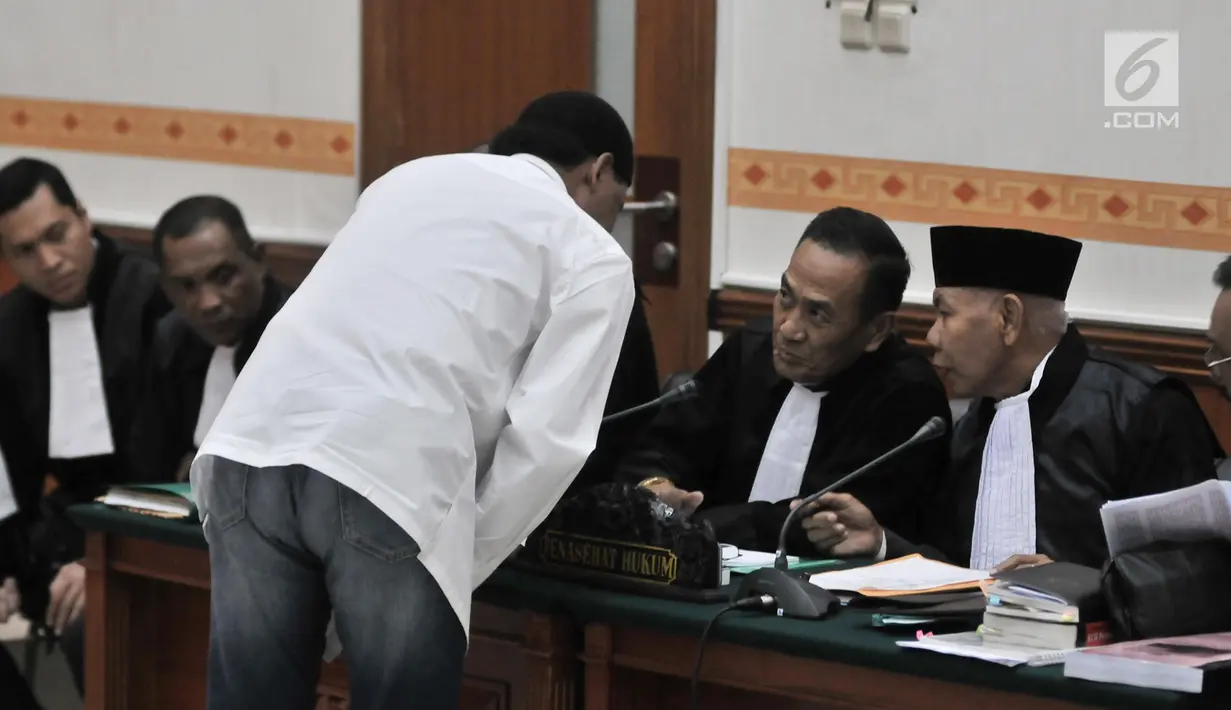 Terdakwa Hercules Rosario Marshal berkonsultasi dengan penasihat hukum saat menjalani sidang perdana di PN Jakarta Barat, Rabu (16/1). Hercules mengaku berencana melangsungkan umrah usai persidangan kasusnya selesai. (Merdeka.com/Iqbal Nugroho)