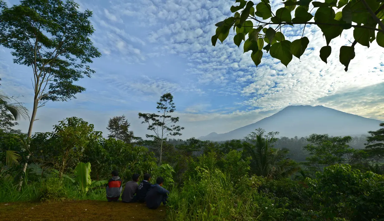 Warga melihat Gunung Agung di Karangasem di pulau resor Bali, Indonesia (24/9).  Gunung Agung kemungkinan akan meletus untuk pertama kalinya sejak lebih 50 tahun lalu. (AFP Photo/Sonny Tumbelaka)