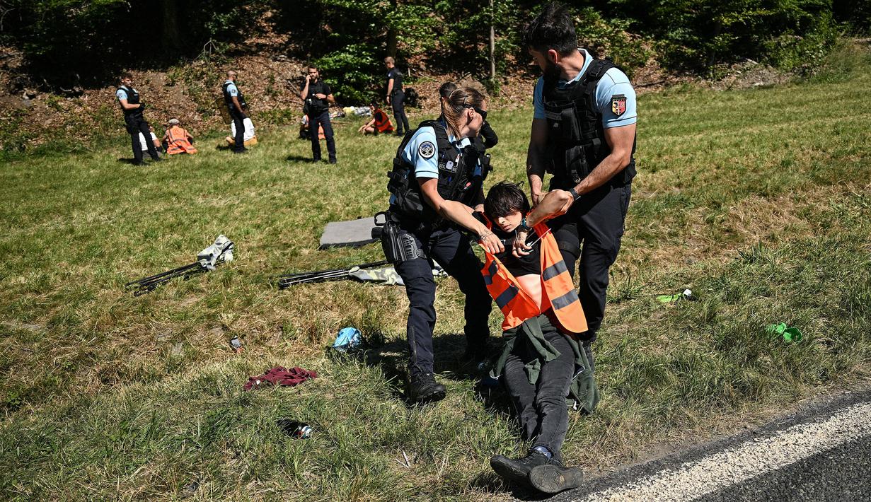 Polisi Prancis memindahkan sejumlah pengunjuk rasa lingkungan setelah aksi protes mereka menghentikan sementara balapan pada etape ke-10 Tour de France, antara Morzine dan Megeve, di Pegunungan Alpen Prancis, pada 12 Juli 2022. (AFP/Marco Bertorello)