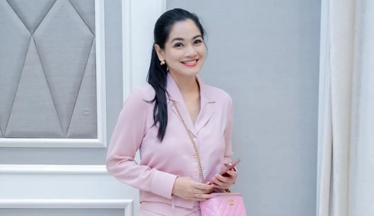 Jika ingin tampilan lebih kasual, Titi mengenakan setelan warna pink terdiri dari kemeja crop top lengan panjang dan celana panjang. Sambil membawa tas Chanel warna serasi. [@titi_kamall]