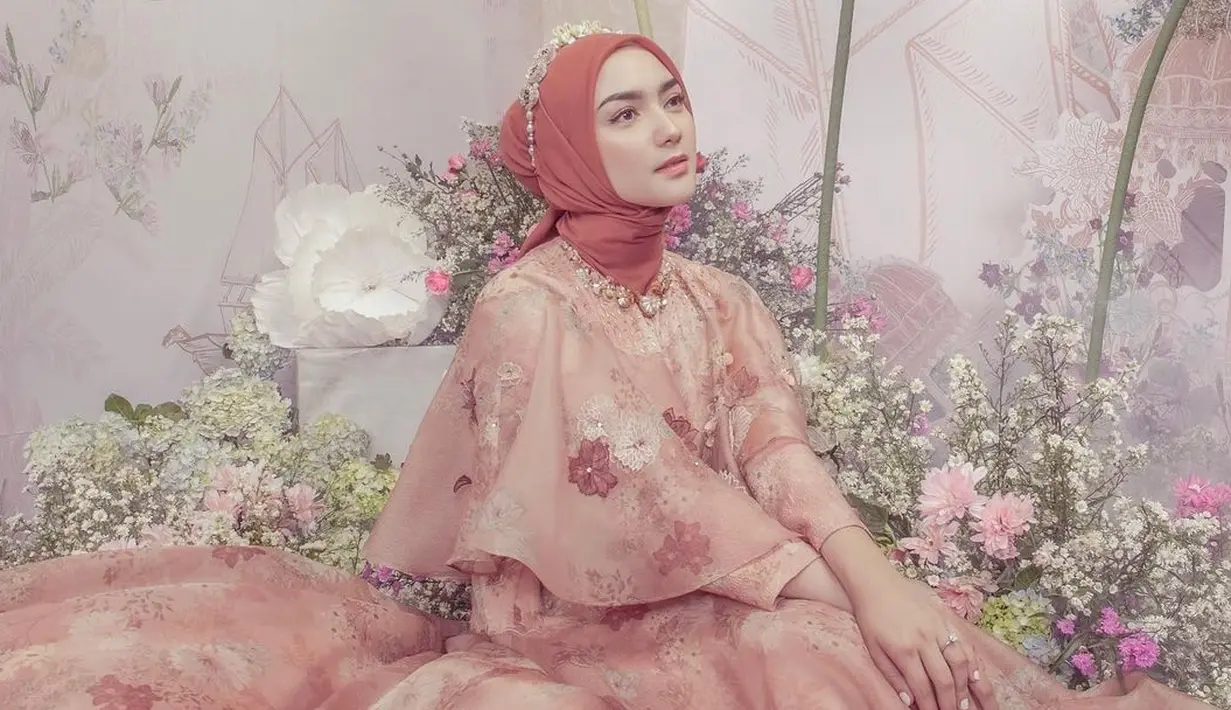 <p>Tampil totalitas bak princess, di sini Citra Kirana terlihat mengenakan dress yang tak kalah cantik bernuansa oranye dengan motif bunga dari bordir dan perpaduan bahan-bahan yang flowy seperti satin dan organza. Ia padukan dengan jilbab oranye polos dan headpiece yang menyempurnakan penampilannya secara keseluruhan. Foto: Instagram.</p>
