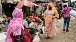 Mame Sey, istri Bara Tambedou, mengenakan masker saat ke pasar membeli makanan pada bulan suci Ramadan, di Dakar, Senegal, 25 April 2020. Tahun ini, banyak keluarga menjalankan Ramadan di rumah dengan larangan pertemuan publik dan jam malam untuk menekan penyebaran Covid-19. (AP/Sylvain Cherkaoui)