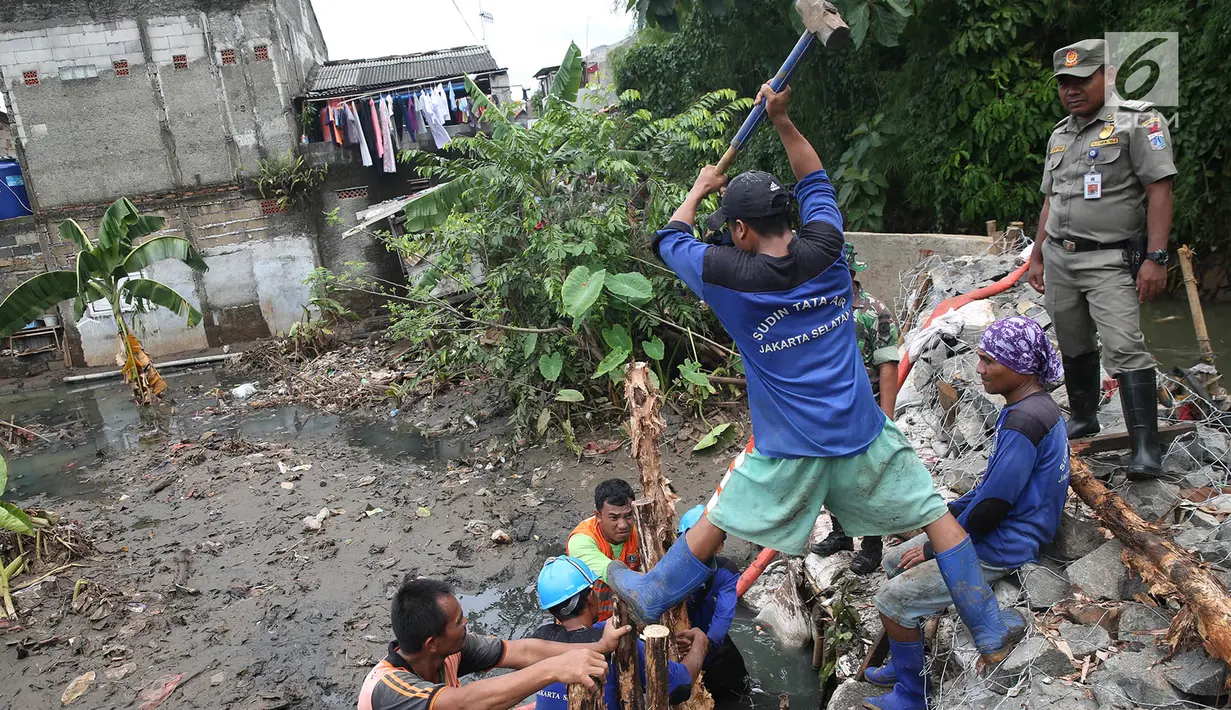 Petugas gabungan bergotong royong memperbaiki tanggul yang jebol di Kelurahan Jatipadang, Jakarta Selatan, Selasa (12/12). Perbaikan tanggul sementara itu dilakukan dengan membuat tanggul pasir lalu menahannya dengan kayu. (Liputan6.com/Immanuel Antonius)