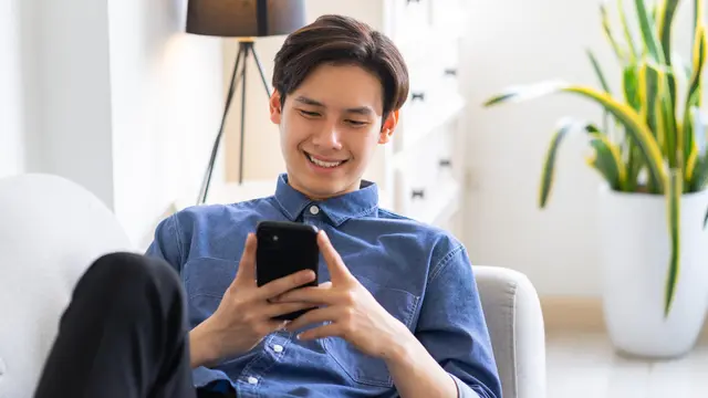 pria ganteng tertawa pegang handphone