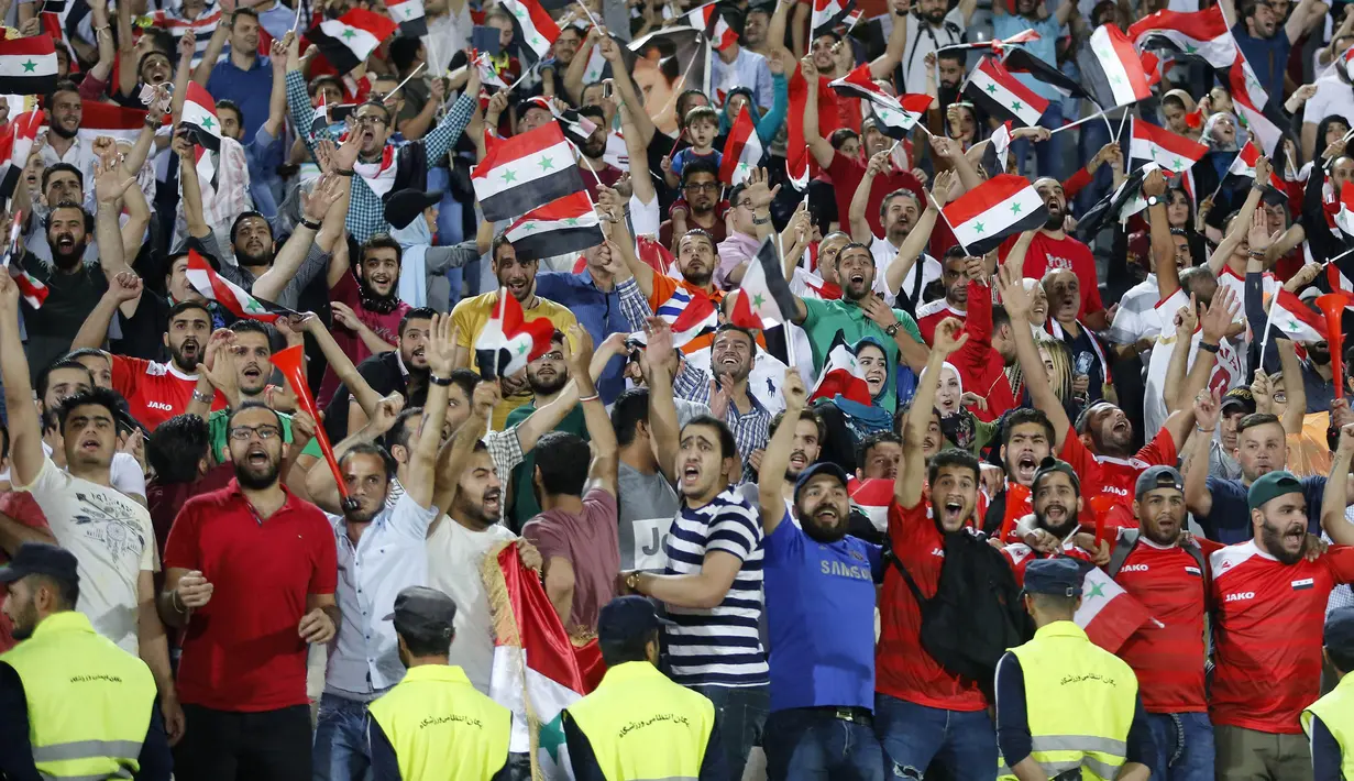 Suporter Suriah berpesta usai menahan imbang Iran 2-2 pada laga kualifikasi Piala Dunia 2018 di Stadion Azadi, Taheran, Selasa (5/9/2017). Finis urutan tiga grup A, Suriah lolos ke babak playoff untuk menantang Australia. (AFP/Atta Kenare)
