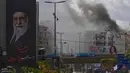 Kepulan asap terlihat di balik potret mendiang Pemimpin Tertinggi Iran, Ayatollah Ali Khamenei, setelah serangan udara Israel di Dahiyeh, pinggiran selatan Beirut, Lebanon, Senin, 30 Maret 2026. Serangan udara Israel kembali menghantam wilayah Dahiyeh, pinggiran selatan Beirut, Lebanon. (AP Photo/Hassan Ammar)