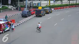 Seorang pengendara sepeda melintas di Kawasan Bundaran HI, Jakarta, Rabu (15/2). Suasana lalu lintas di kawasan tersebut terlihat sepi di karenakan libur pemilihan Gubernur DKI. (Liputan6.com/Angga Yuniar)