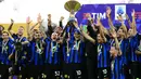 Penyerang Inter Milan #10 Lautaro Martinez mengangkat trofi Liga Italia 2023/2024 bersama rekan satu timnya dalam upacara penyerahan gelar scudetto usai menghadapi Lazio pada laga giornata 37 Serie A 2023/2024 di Giuseppe Meazza, Minggu (19/5/2024) malam WIB. (Marco BERTORELLO / AFP)