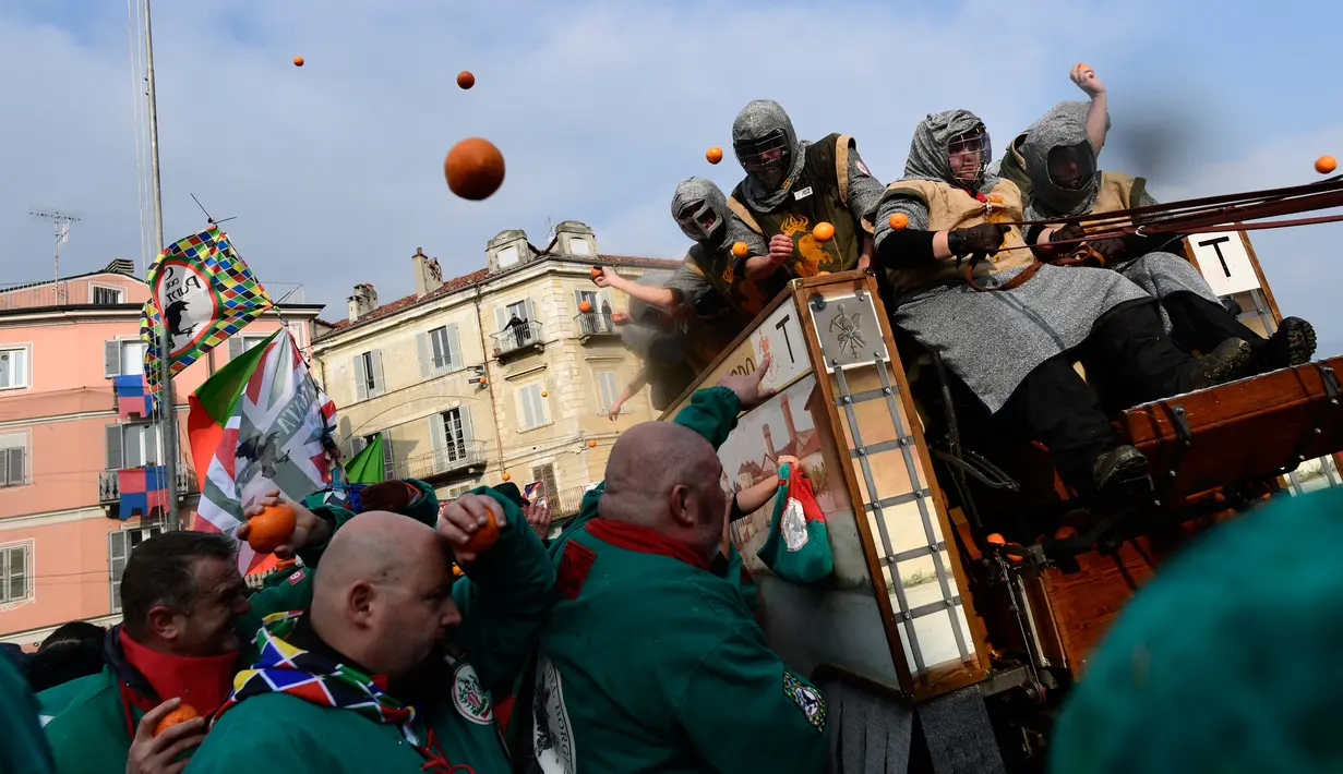 Peserta dari atas kereta kuda melempari jeruk kepada warga pada festival "Battaglia delle Arance" (Perang Jeruk) di kota kecil dekat Turin, Minggu (11/2). Para pejalan kaki yang melempari pasukan di atas gerobak yang mewakili Napoleon. (MIGUEL MEDINA/AFP)