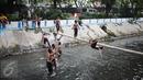 Keceriaan saat anak-anak bermain di aliran Kali Gresik di Jalan Muhammad Yamin, Menteng, Jakarta, Minggu (26/2). Kondisi kali di Kota Jakarta yang bersih dan terawat mendapatkan respon positif bagi warga Ibu Kota. (Liputan6.com/Faizal Fanani)